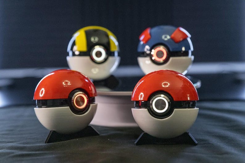 Handmade LED Pokéball opened on its display stand with Pokémon cards